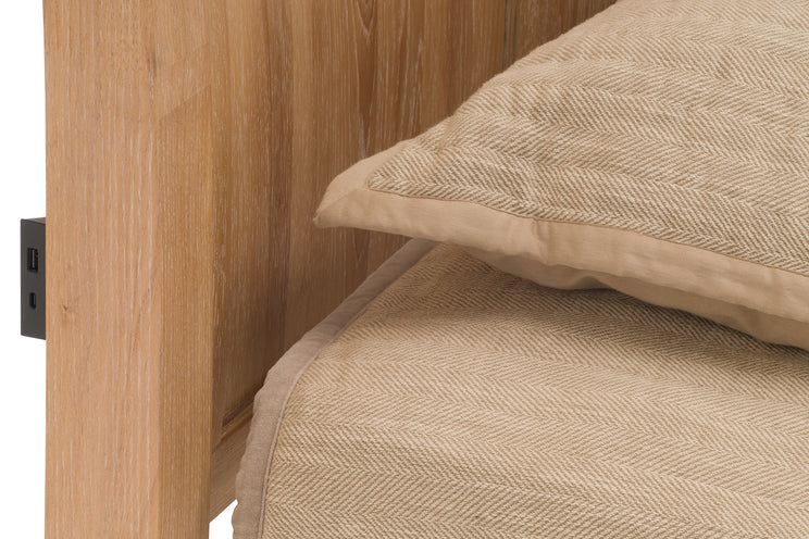 Close-up of a wooden headboard with a beige textured pillow and blanket.